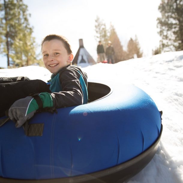 Boy tubes downhill Nakoma Play Hill